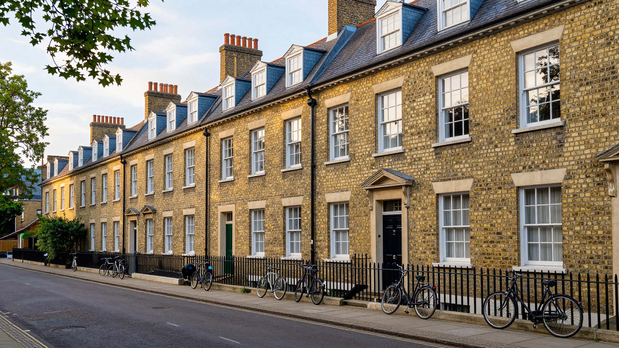 A Cambridge street of Victorian gault-brick terraced houses with grey slate roofs and tall chimney stacks
