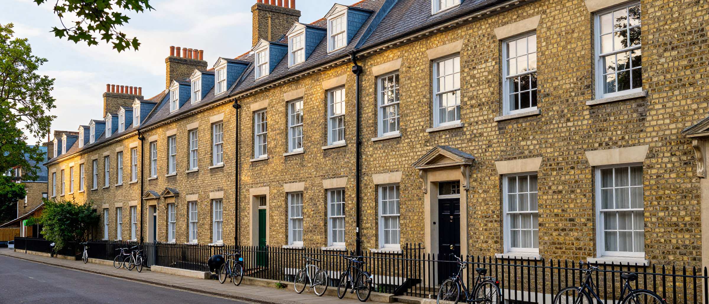 A Cambridge street of Victorian gault-brick terraced houses with grey slate roofs and tall chimney stacks