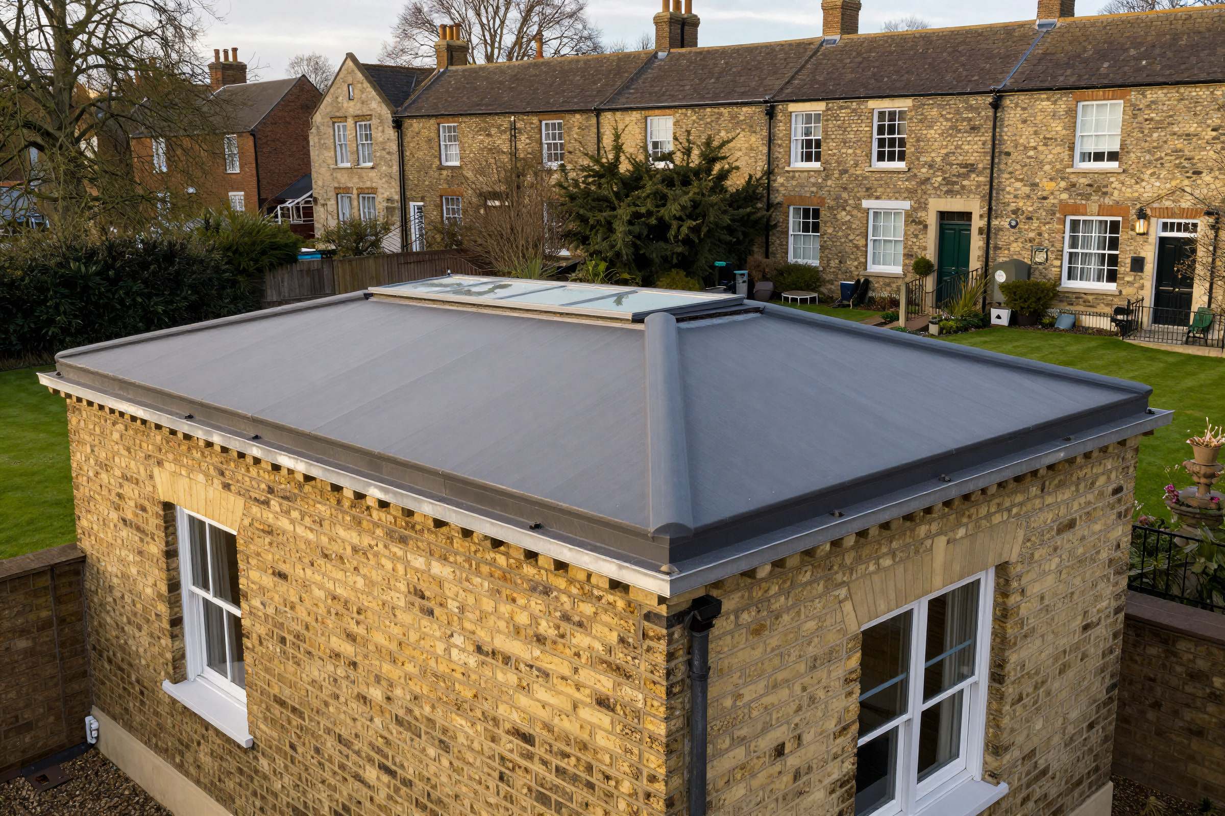 A newly finished charcoal flat roof with a roof light on the rear extension of a gault-brick terrace